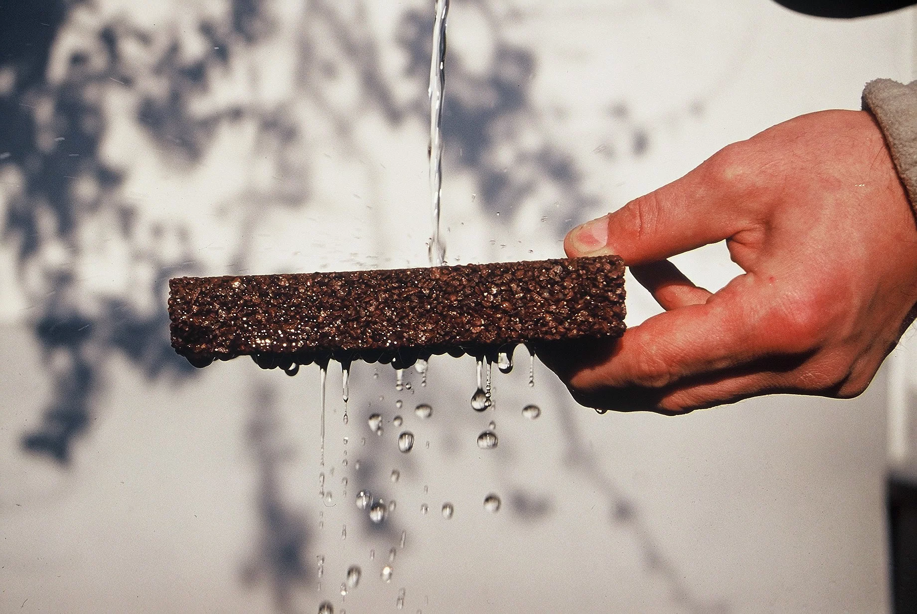 A hand is holding a piece of TerraWay surfacing that allows water to seep through